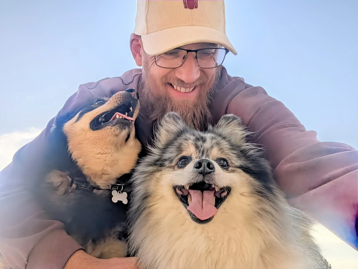 James, who makes SayGday, with his two dogs, Luna and Stormi, all three grinning at the camera